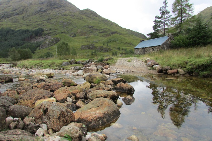 A picture of a Scottish bothy at the foot of a hill