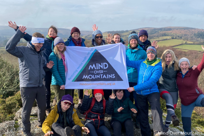A group of hikers holding up a Mind Over Mountains banner at the top of a charity walk
