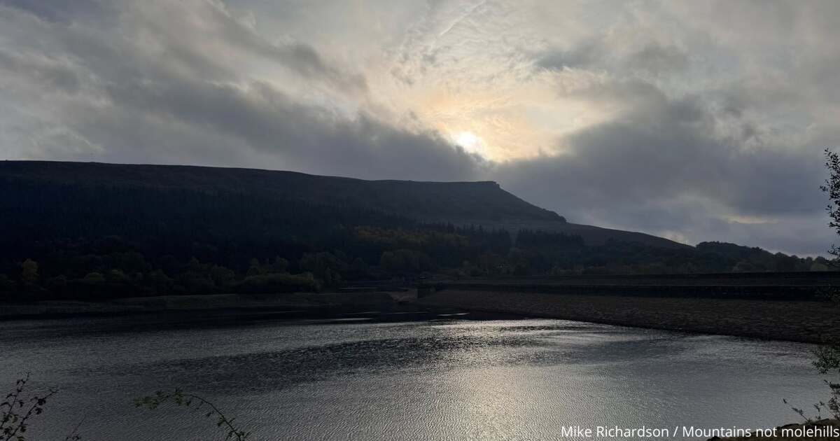 Lady Bower Reservoir with Win Hill in the background and the sun beginning to shine through the clouds