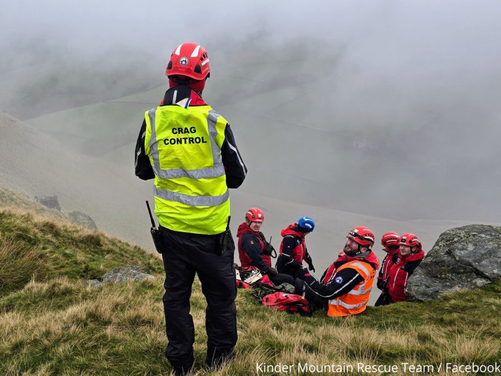 Group of Kinder Mountain Rescue Team sat listening to a supervisor in a yellow high vis vest