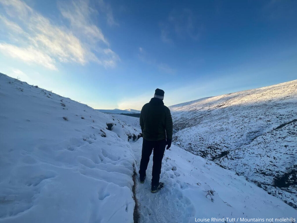 Male hiker on Kinder Scout in the snow with blue sky 