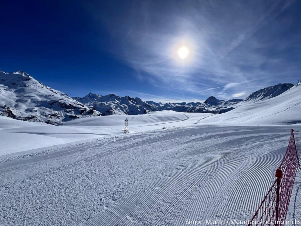Ski slope in Tignes with mountains and the sun in the background