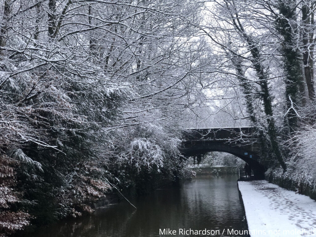 Snow covered canal path in Worsley Village approaching a bridge
