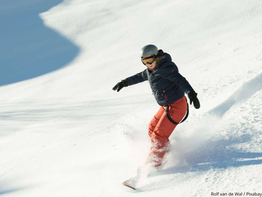 Female snowboarder mid turn on a piste