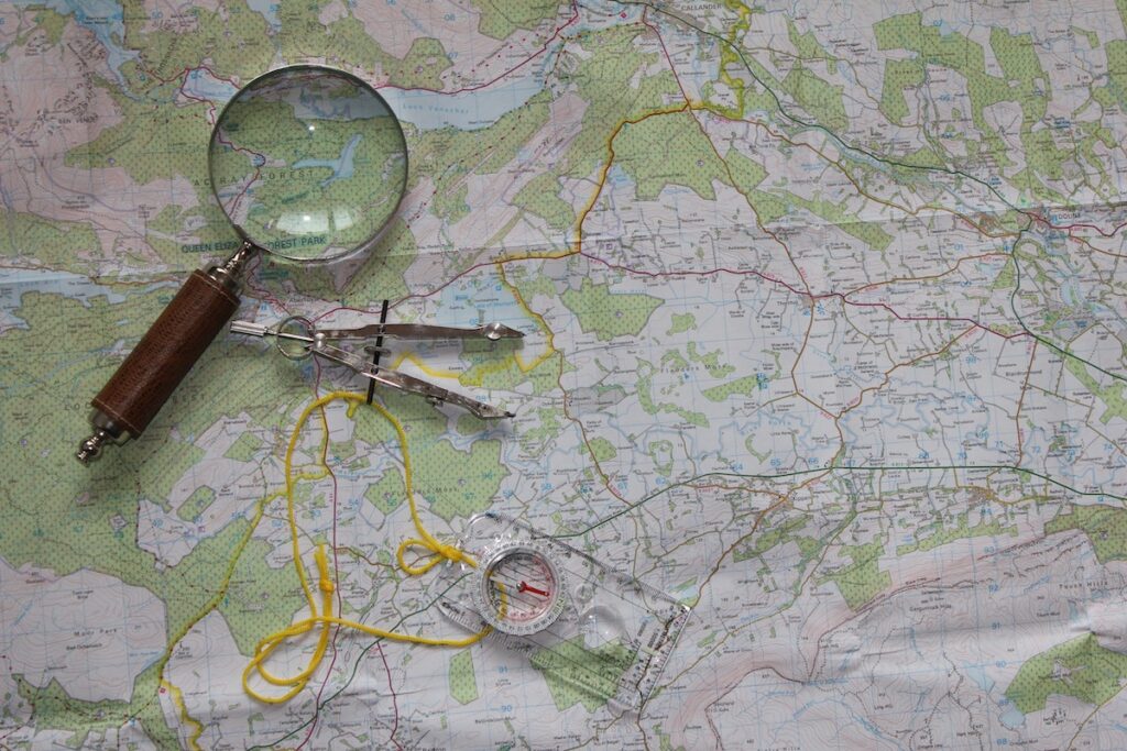 Navigation essentials, paper map, compass and magnifying glass